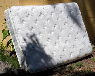 junk removal old mattress outside against house wall in vero beach