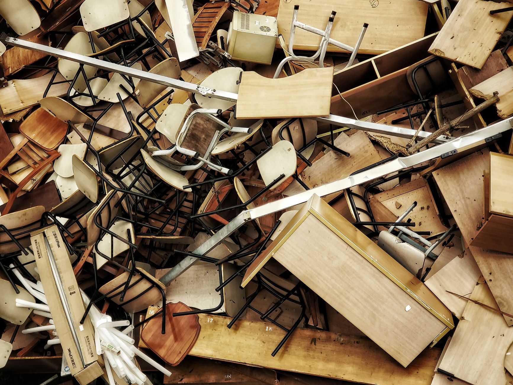 Pile of discarded wooden furniture and chairs viewed from above, similar to old furniture cleared from a Vero Beach home