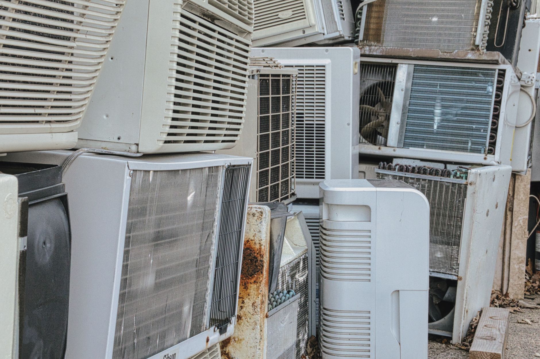 Assorted old air conditioning units stacked outdoors after removal from a Vero Beach property
